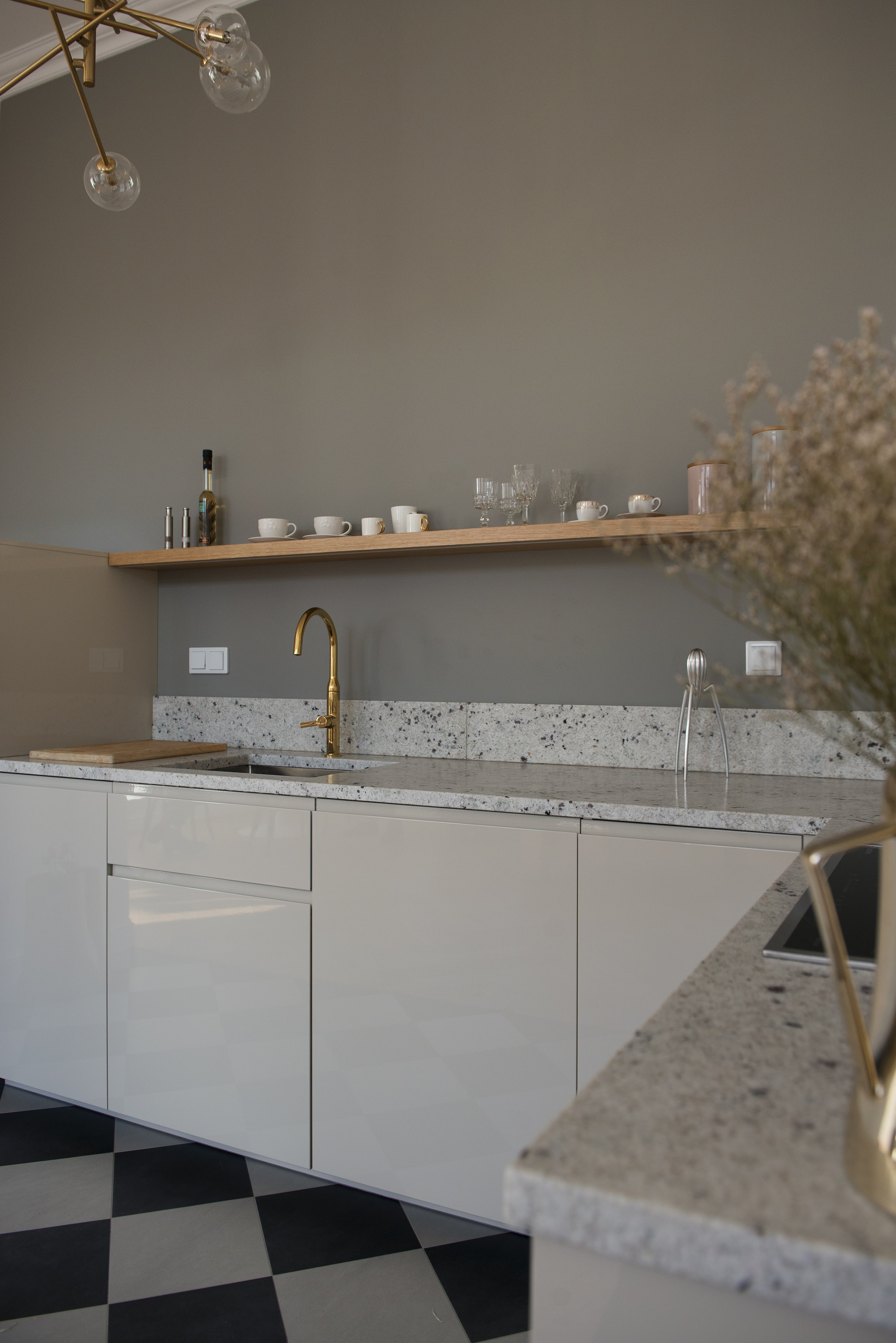 Na podłodze klasyczny wzór szachownicy i dębowa deska, a na blacie naturalny granit.