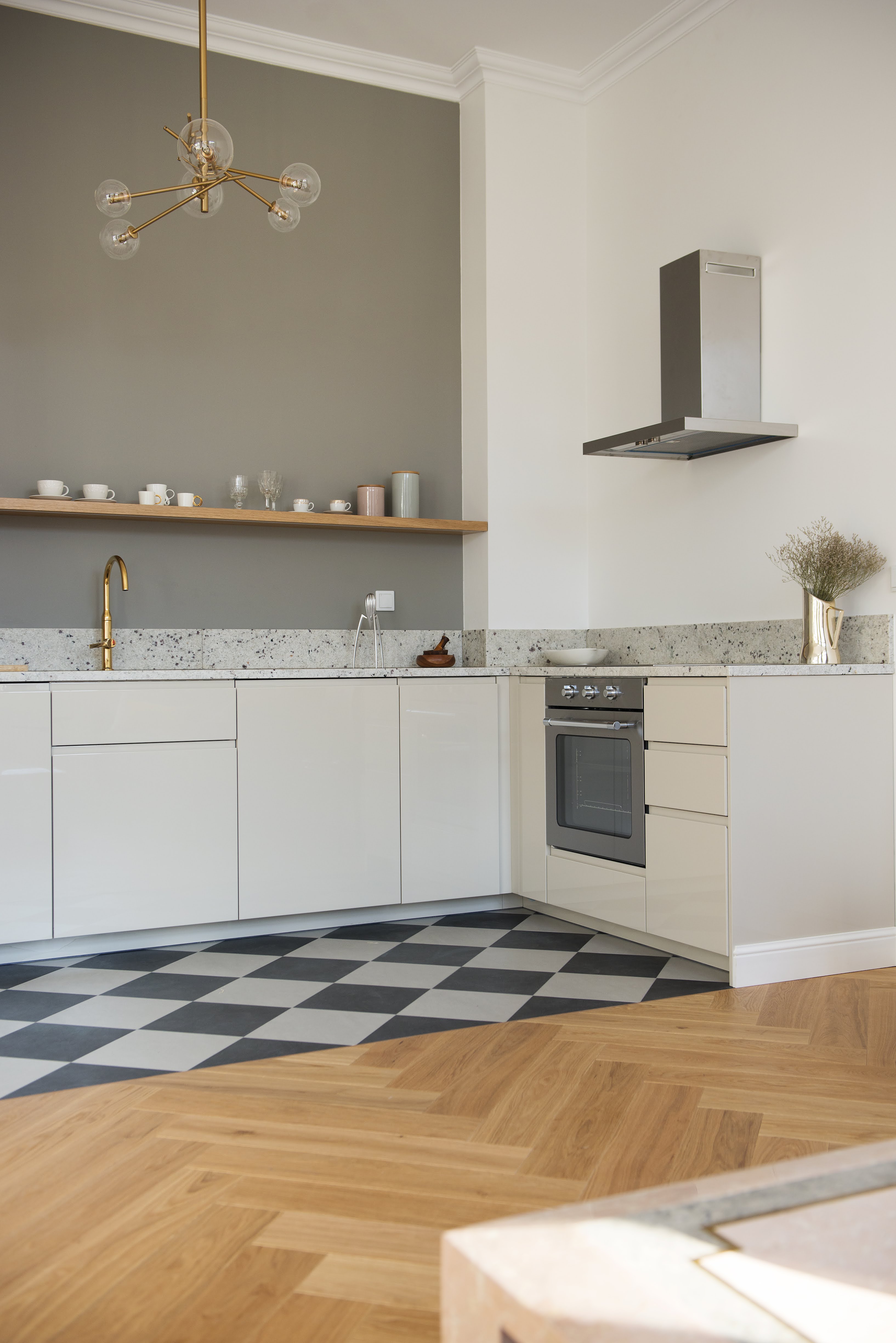 Na podłodze klasyczny wzór szachownicy i dębowa deska, a na blacie naturalny granit.